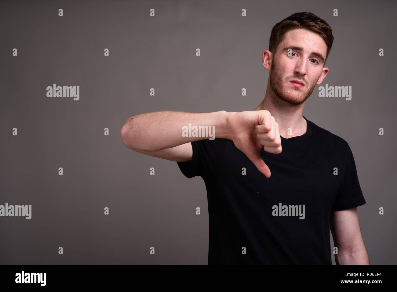 Portrait de jeune homme séduisant contre l'arrière-plan gris Banque D'Images