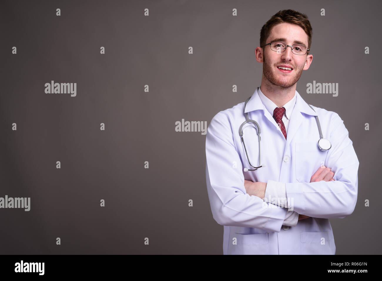 Jeune homme séduisant médecin portant des lunettes contre la zone de gris Banque D'Images