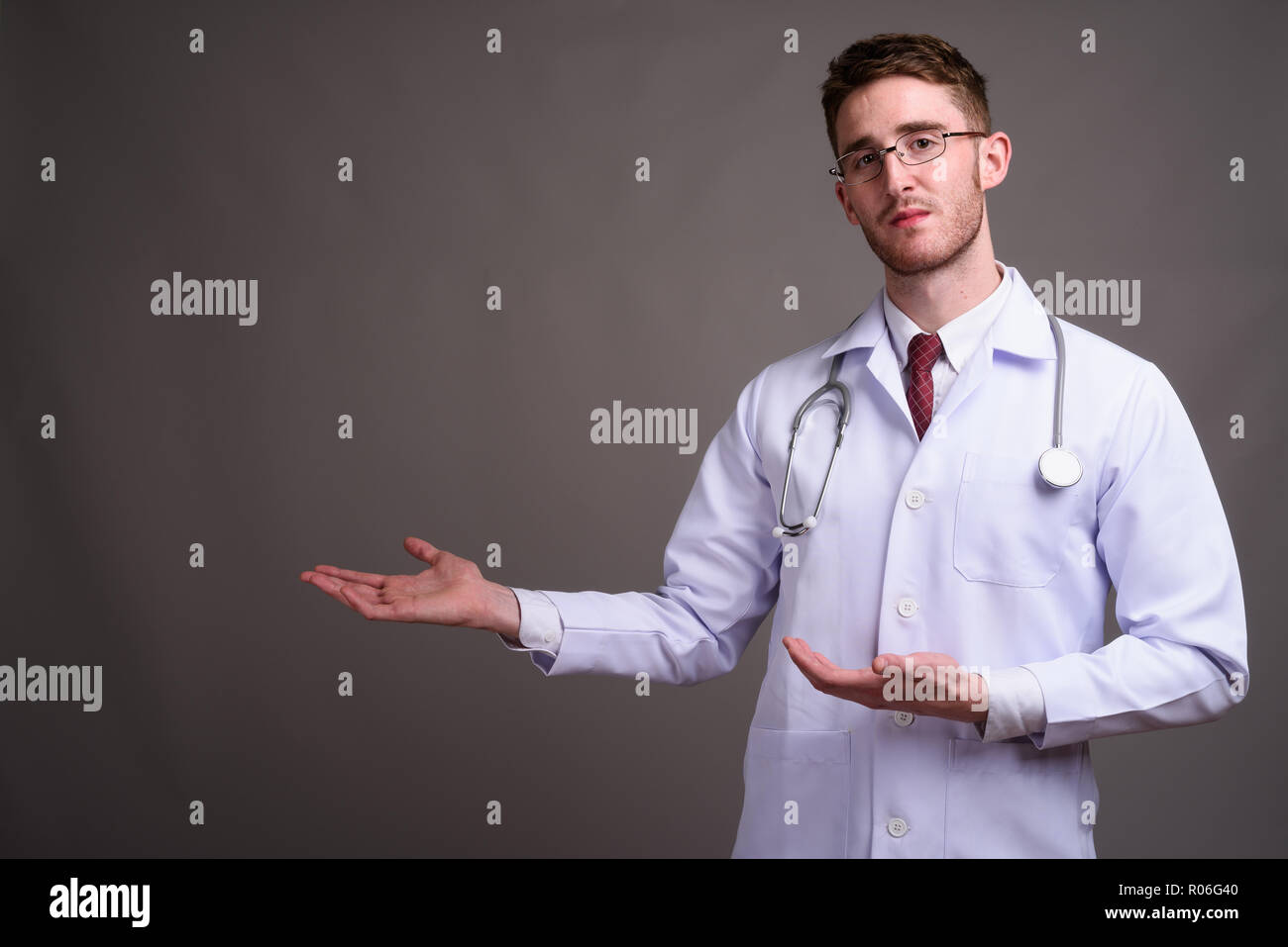 Jeune homme séduisant médecin portant des lunettes contre la zone de gris Banque D'Images