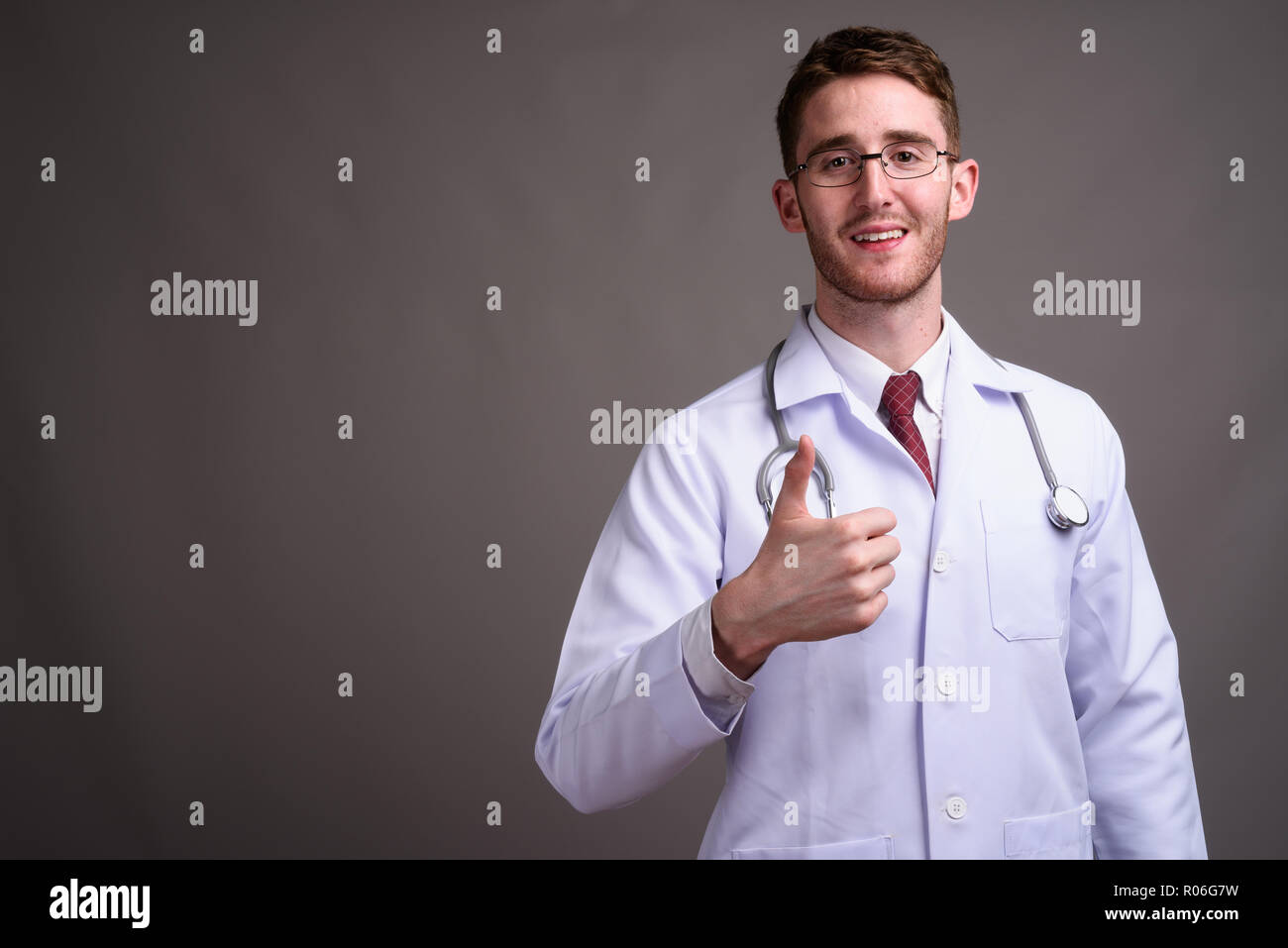 Jeune homme séduisant médecin portant des lunettes contre la zone de gris Banque D'Images