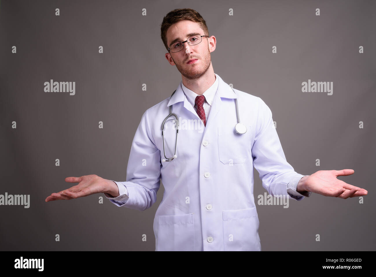 Jeune homme séduisant médecin portant des lunettes contre la zone de gris Banque D'Images