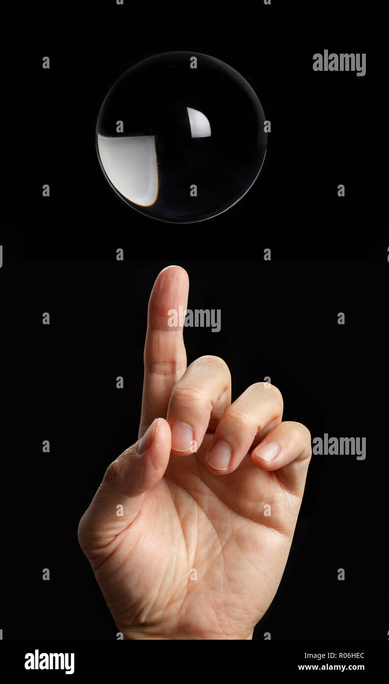Pointer du doigt une boule de cristal transparent avec fond noir. Banque D'Images
