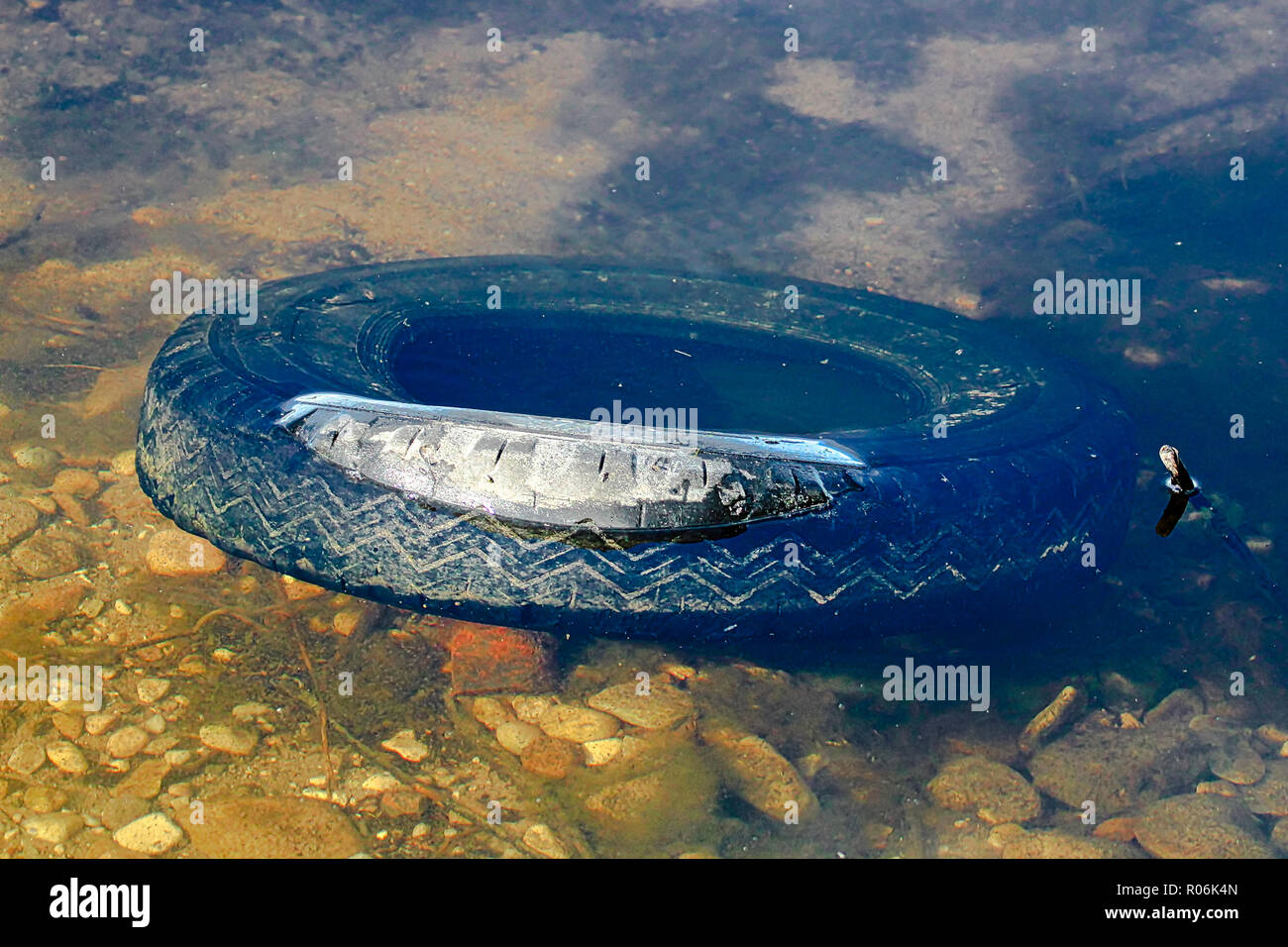 Un pneu abandonné des pneus jetés dans l'eau Banque D'Images