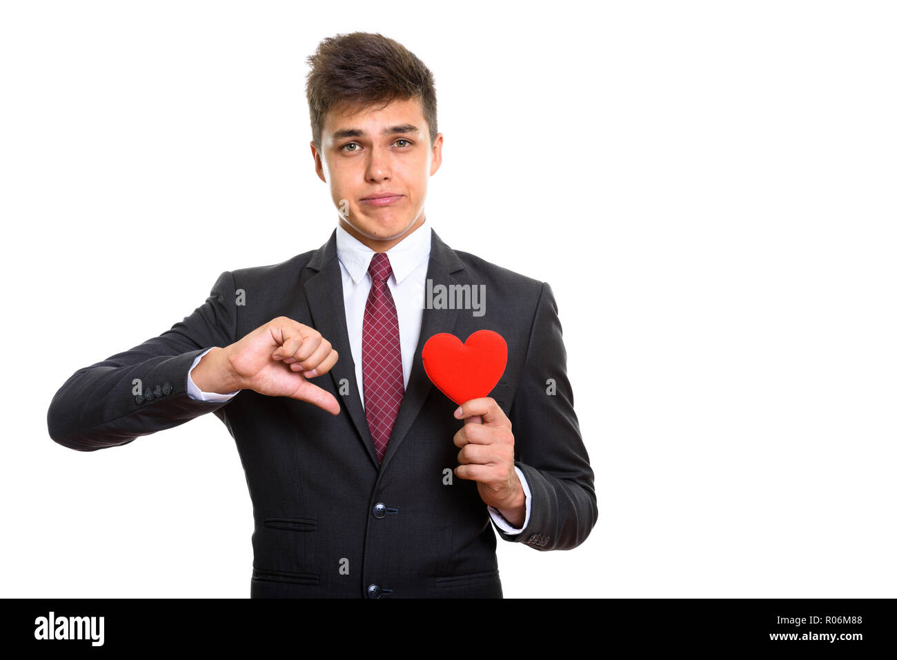 Jeune homme triste giving thumb vers le bas en maintenant le coeur rouge Banque D'Images