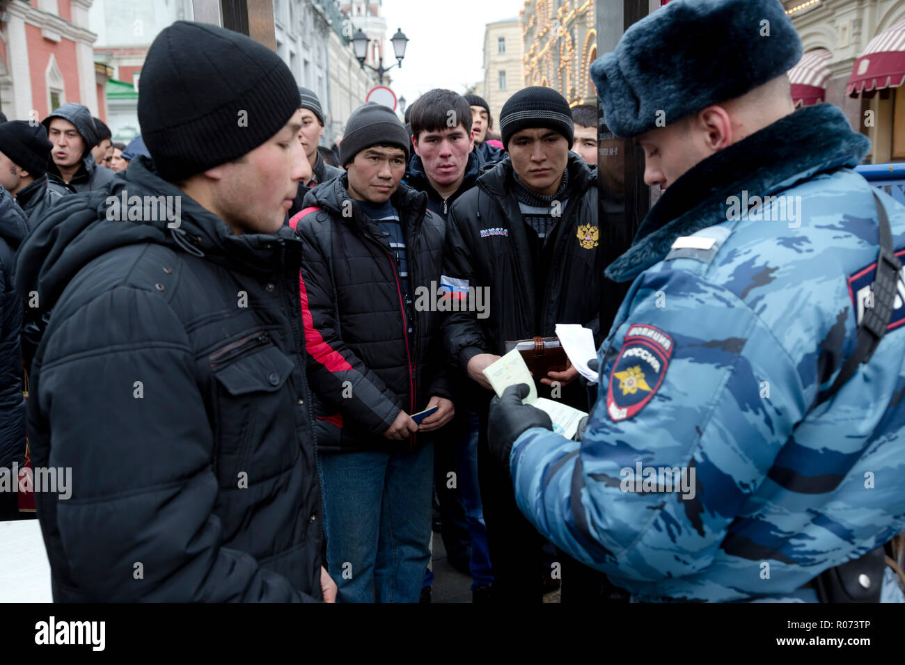 Un policier vérifie les documents de travailleurs migrants d'Asie centrale au cours d'une entrée à la place Rouge à Moscou, Russie Banque D'Images