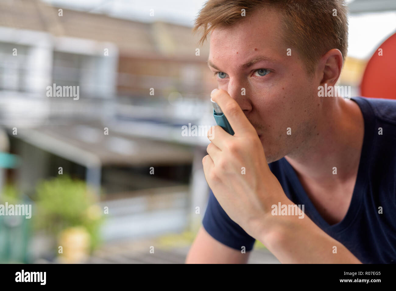 Jeune homme séduisant en utilisant l'asthme inhalateur à la maison Banque D'Images