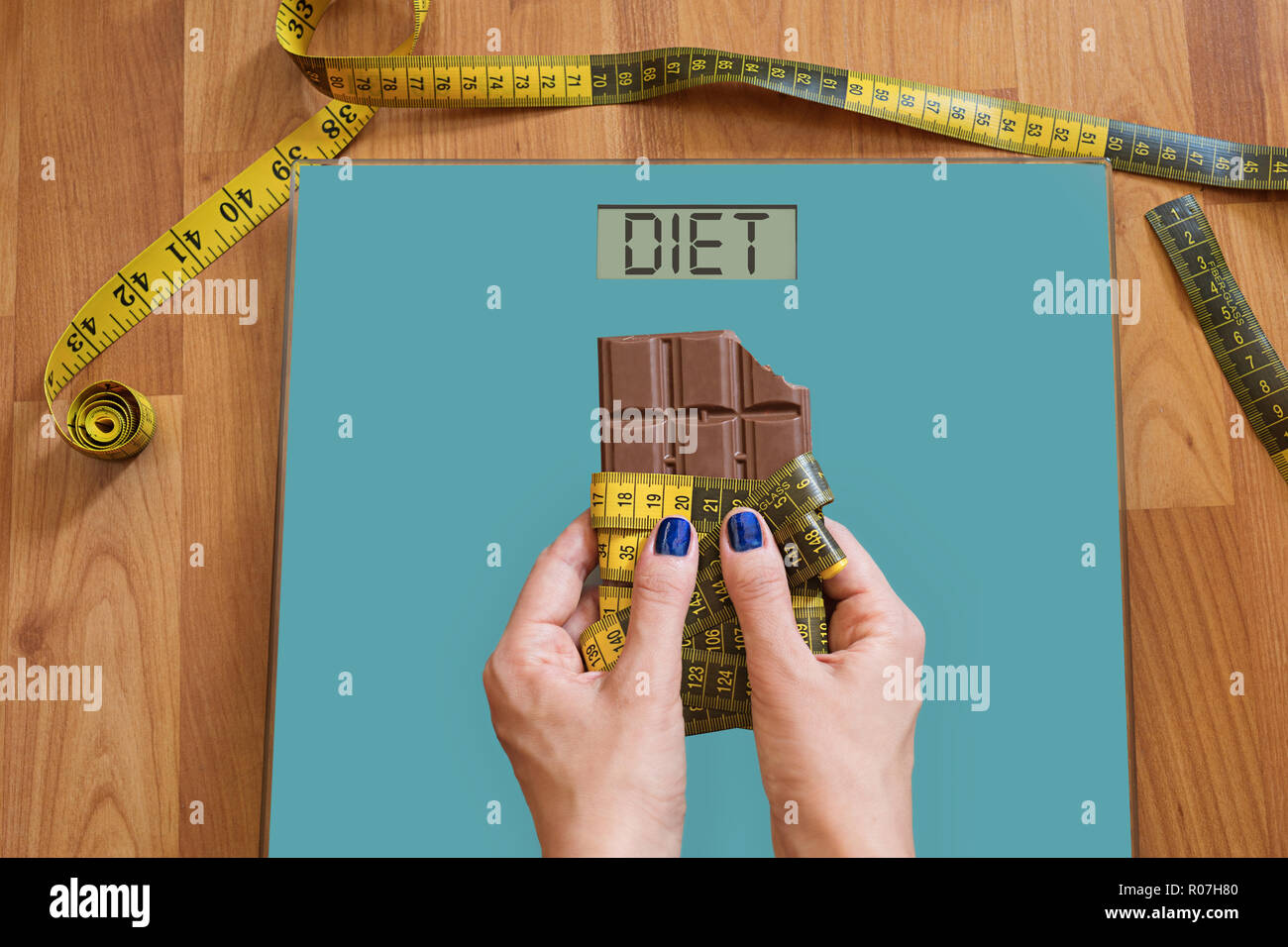 Mains de femme avec des balances pour demander de l'aide à éviter la tentation de manger des sucreries. Arrêter de manger des bonbons, régime alimentaire sain concept avec mesure Banque D'Images