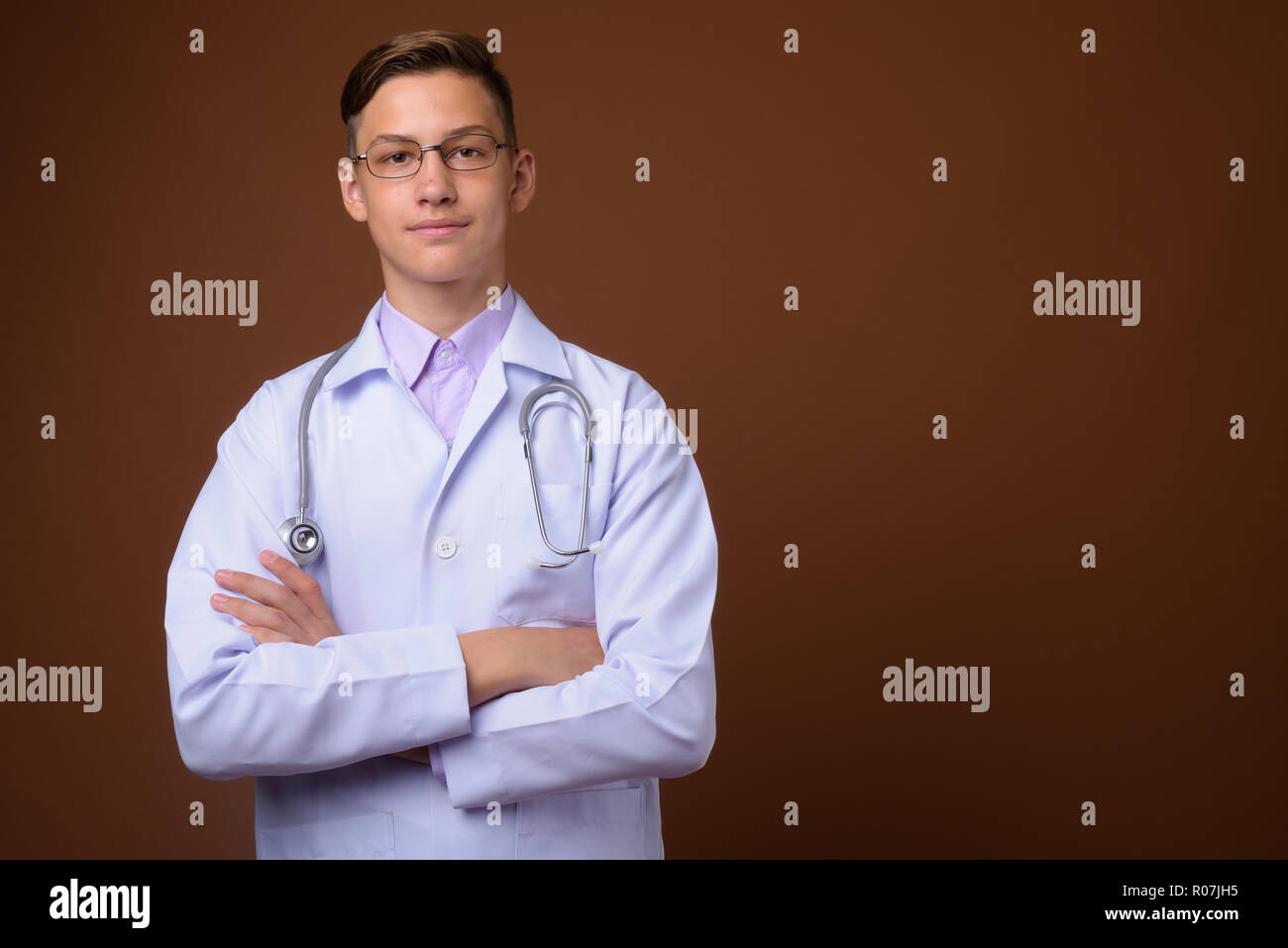 Studio shot of young handsome médecin contre fond brun Banque D'Images