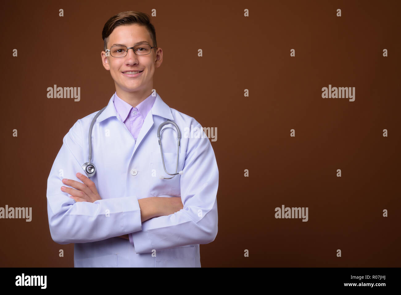 Studio shot of young handsome médecin contre fond brun Banque D'Images