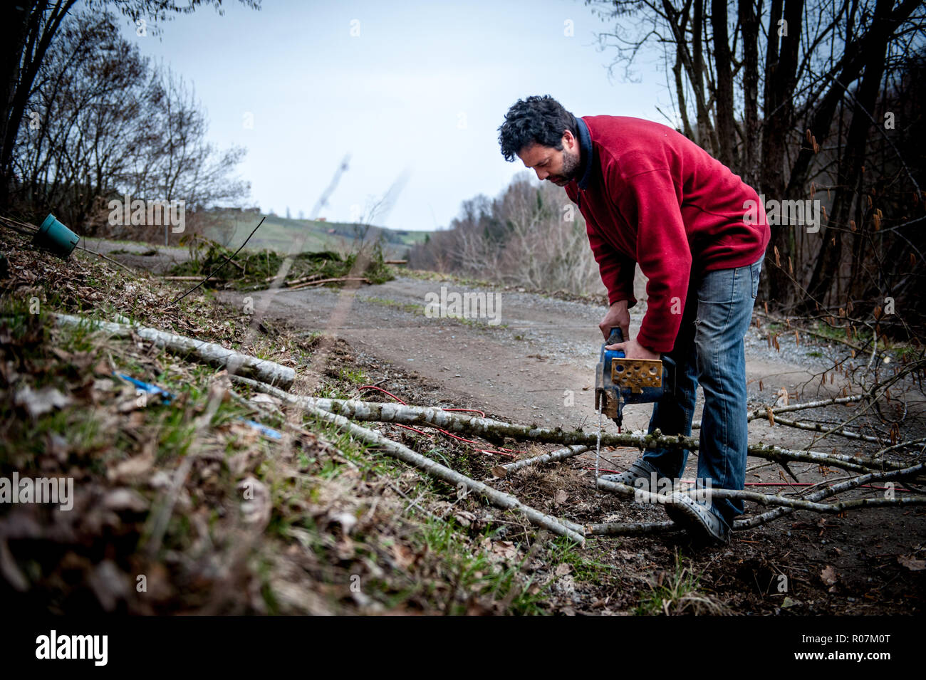 L'homme à l'aide d'une tronçonneuse sans aucun équipement de protection très mauvaises conditions de santé et de sécurité. Banque D'Images