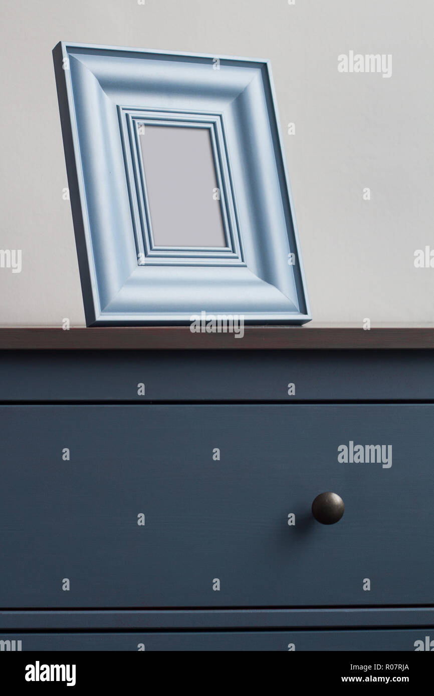 Voir le détail avant verticale de square d'épaisseur sur cadre photo en bois vintage bleu commode avec poignées noires contre le mur dans la lumière naturelle copie Banque D'Images