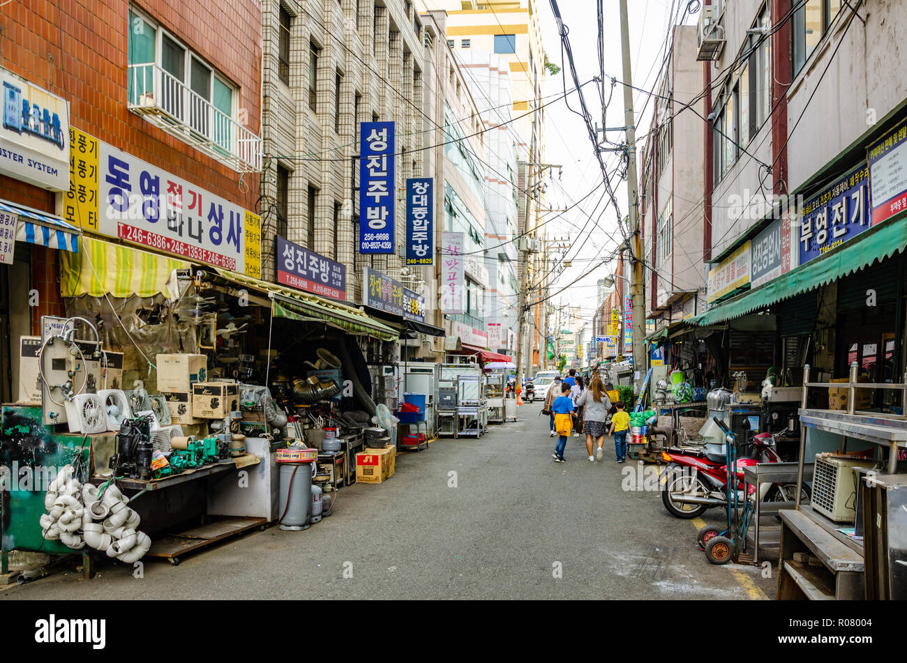 Câbles électriques aériens sillonnent une rue bordée de magasins de matériel à Busan, Corée du Sud. Banque D'Images