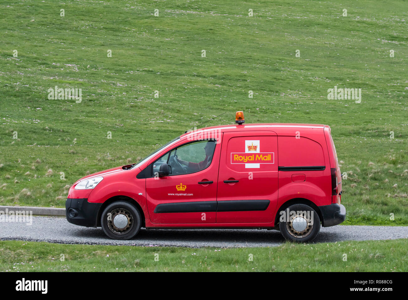 Postman driving red Peugeot Partner Royal Mail poster van le long de la route déserte en Shetland, Écosse, Royaume-Uni Banque D'Images