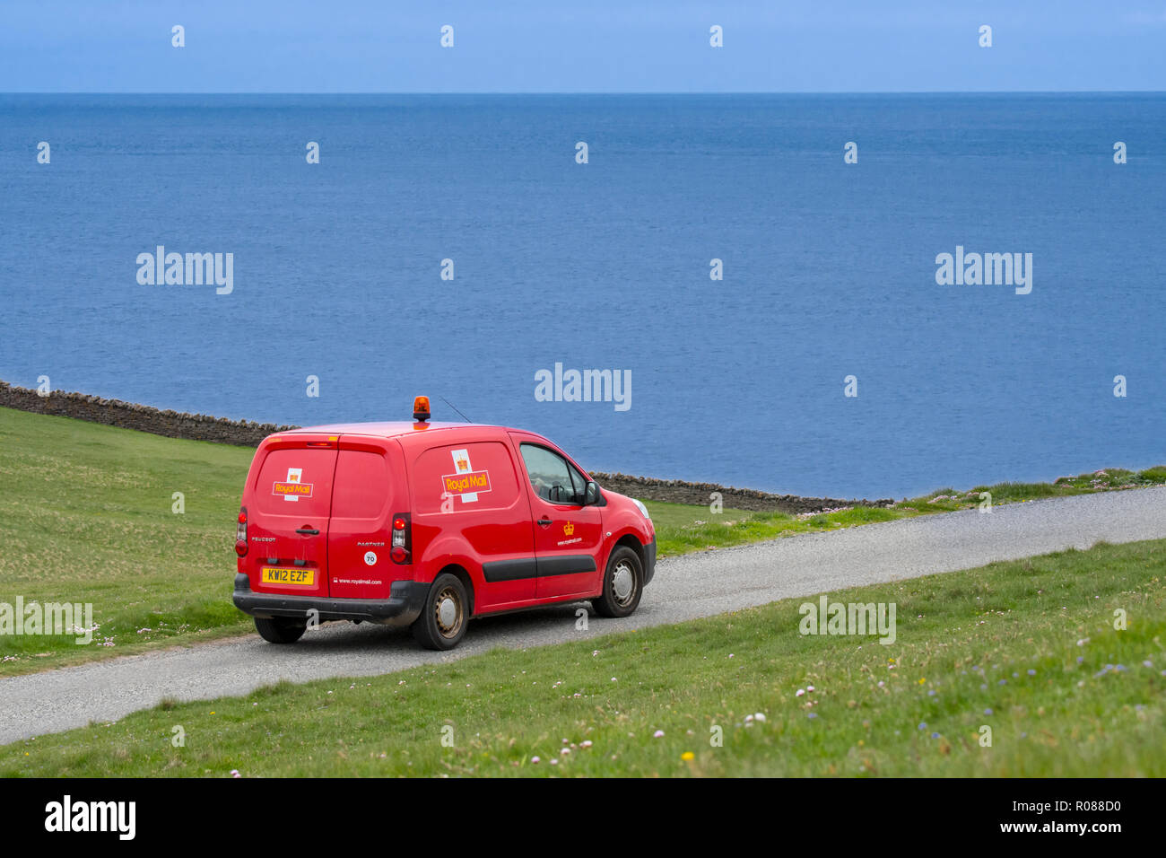 Postman driving red Peugeot Partner Royal Mail poster van le long de la route côtière de désolation en Shetland, Écosse, Royaume-Uni Banque D'Images