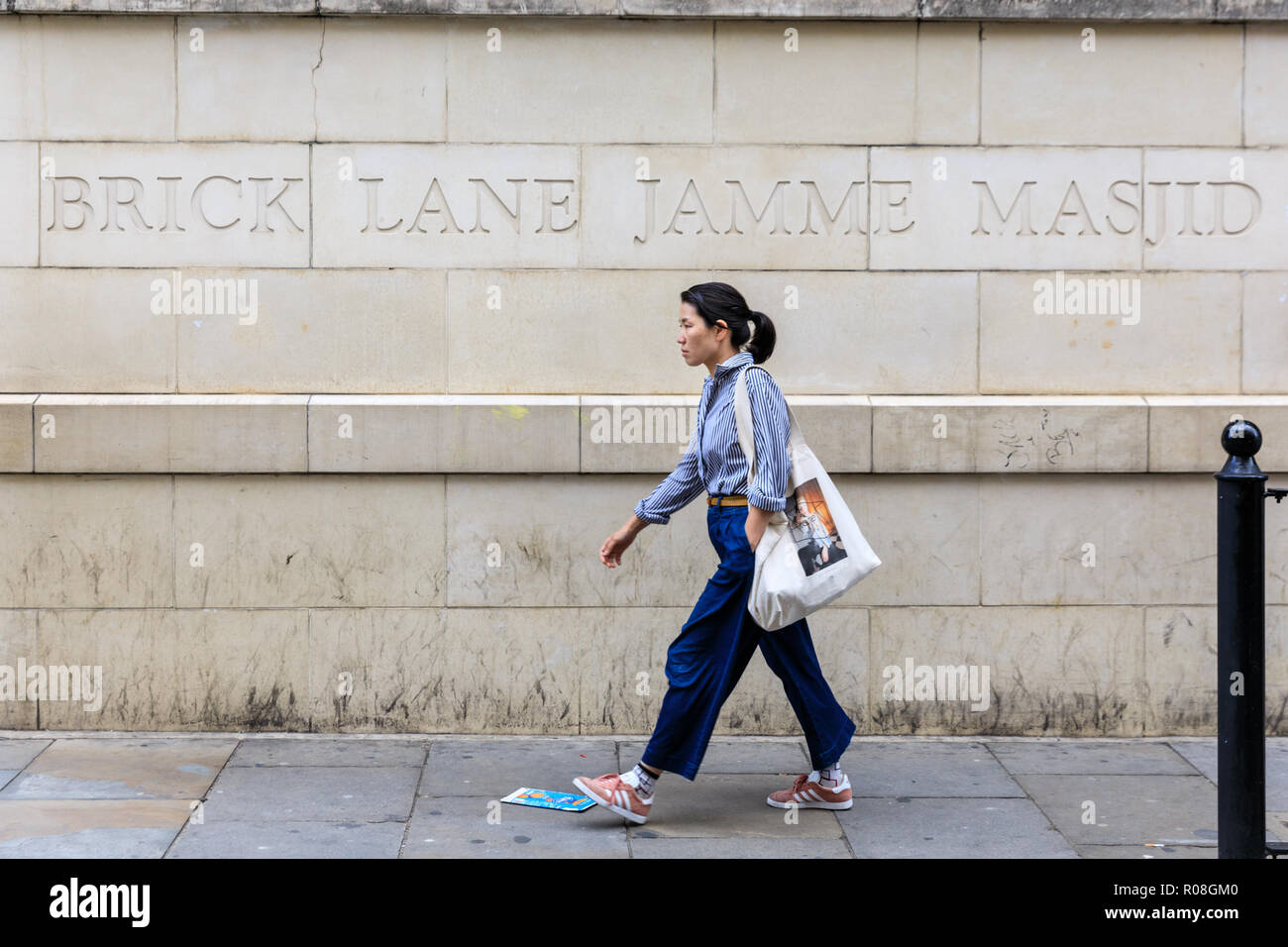 Une femme marche dernières Brick Lane Jamme Masjid, mosquée de Brick Lane dans l'Est de Londres, UK Banque D'Images