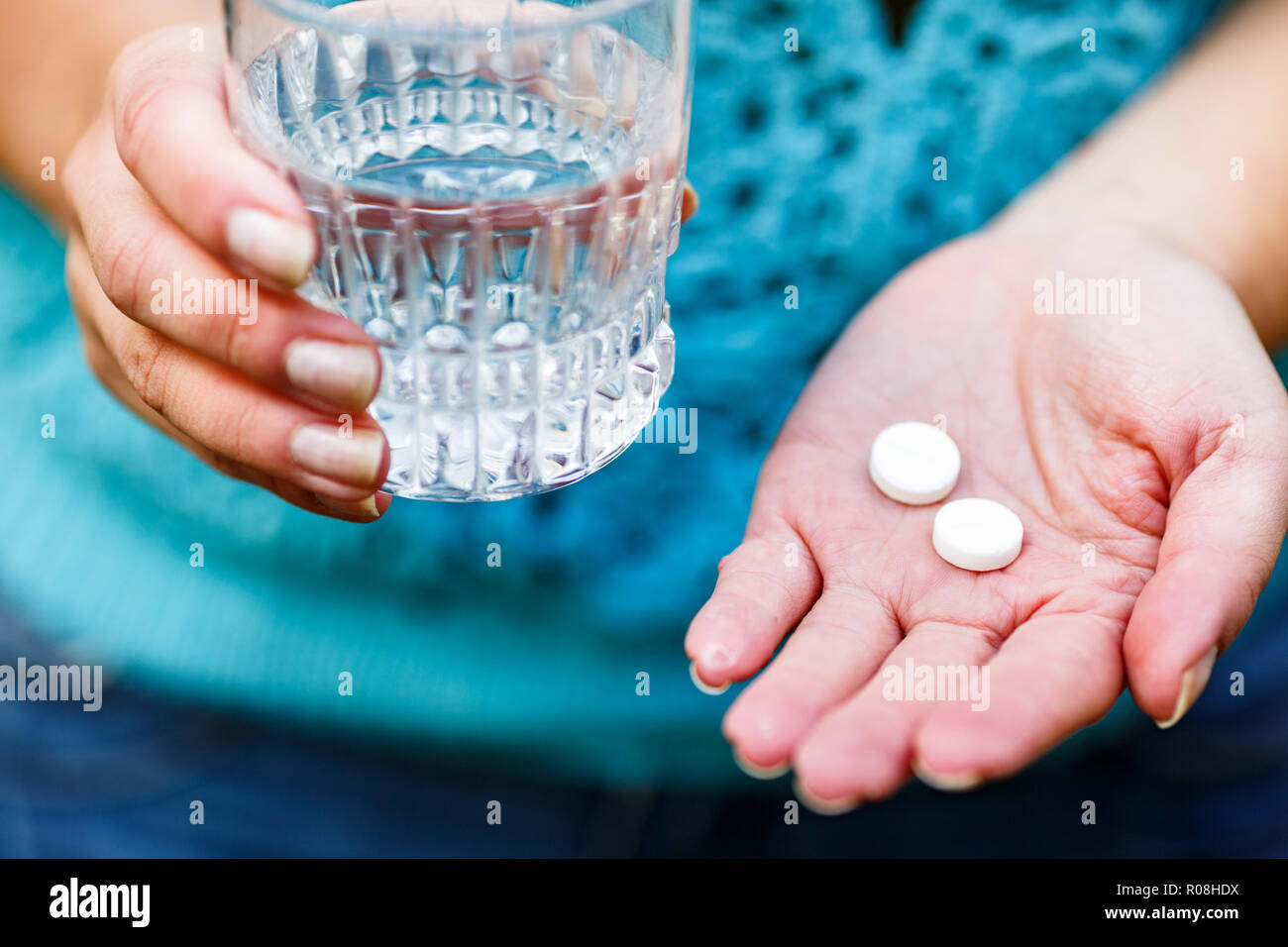Pilules médical blanc et un verre d'eau in women's hands.remèdes pour les maux de tête et douleurs menstruelles Banque D'Images
