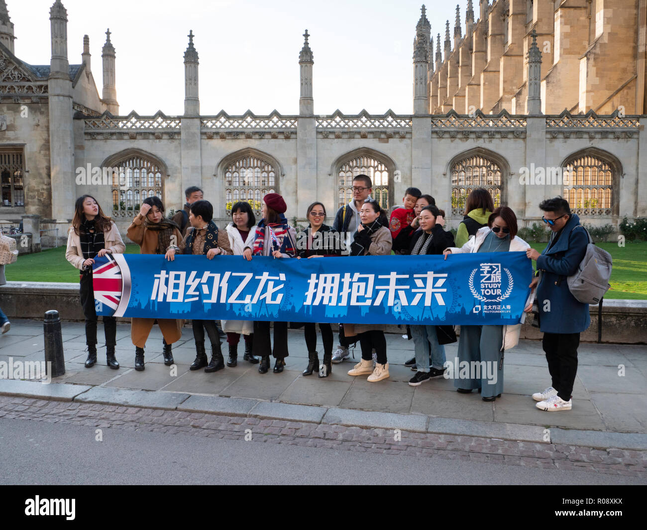 Un grand groupe de touristes chinois debout dans King's Parade Cambridge UK tenant une bannière. Banque D'Images