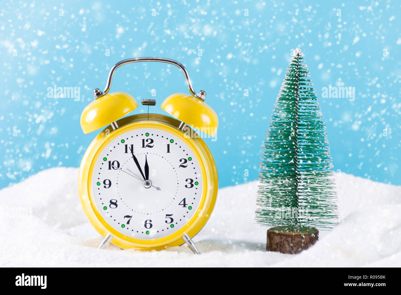 Réveil rétro et sapin de Noël sur la neige et il neige journée d'hiver. Réveil est de couleur jaune et les flocons tomber. Noël et Nouvel An Banque D'Images