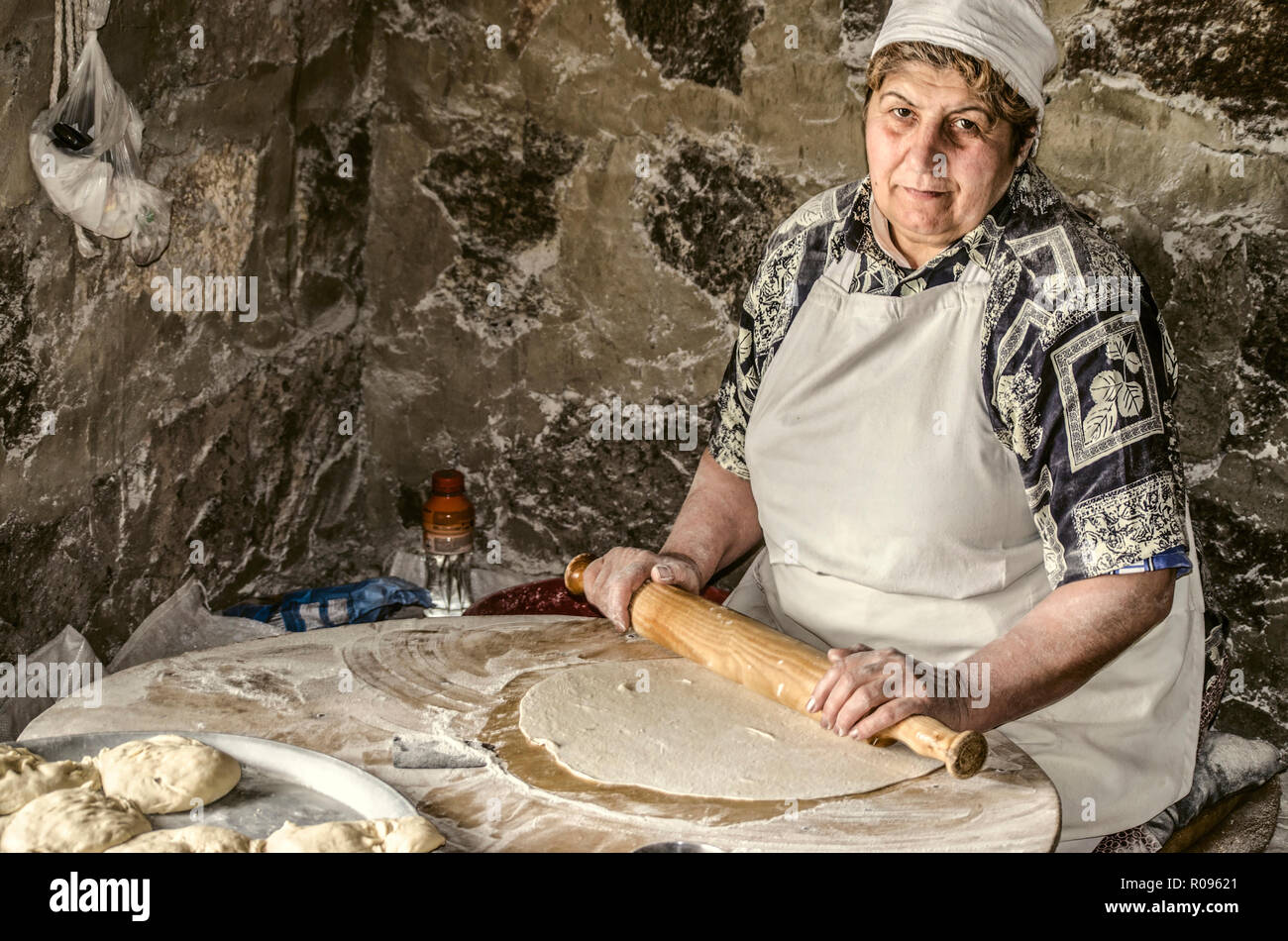 Ashtarak,Arménie,19,Février 2018 : femme arménienne de rouleaux sur la pâte d'un rouleau à pâtisserie en bois en feuilles très minces pour le traditionnel pain lavash en th Banque D'Images