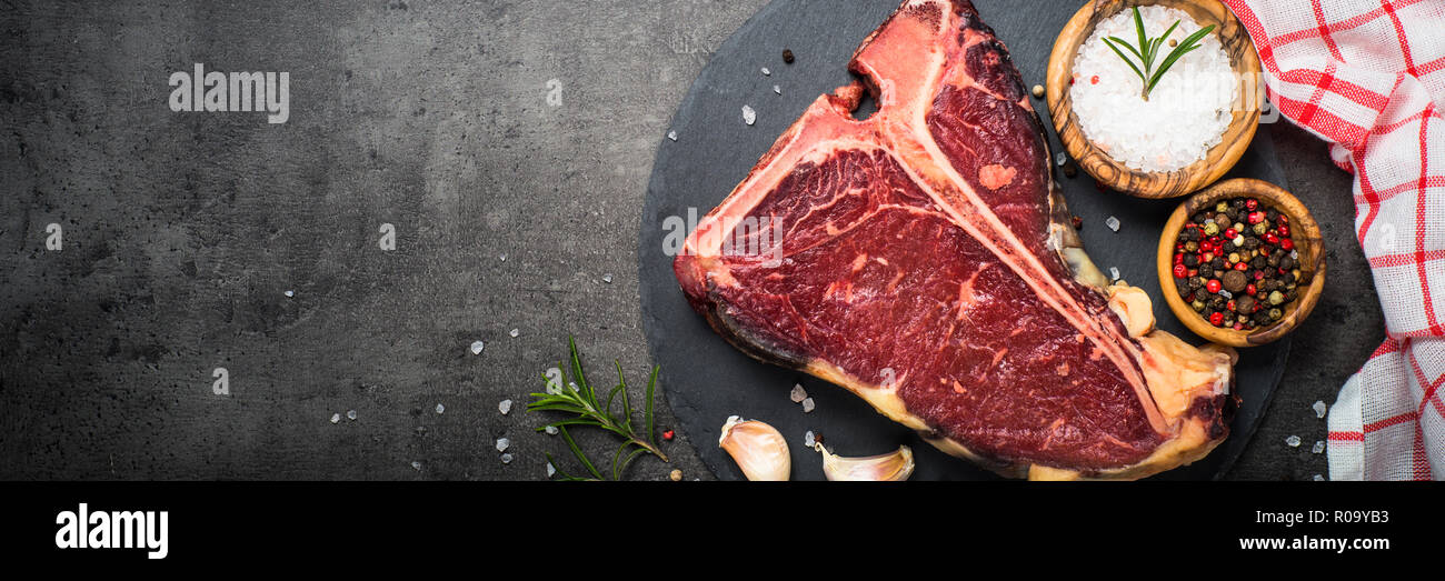 T-bone steak de boeuf sur fond noir avec des épices. Bannière long format. Banque D'Images T-bone steak de boeuf sur fond noir avec des épices. Bannière long format. Banque D'Images