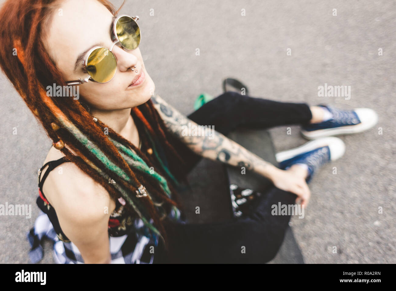 Jeune fille avec des dreadlocks et tatouage assis dans le parc Banque D'Images