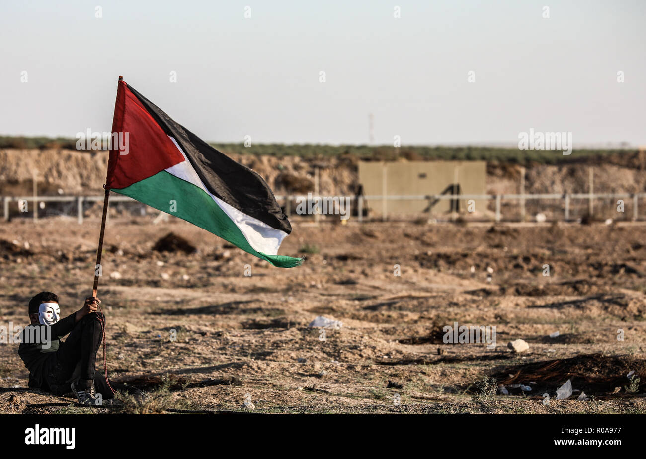 Un manifestant palestinien vu assis tout en tenant un drapeau pendant les affrontements dans l'Est de la ville de Gaza près de la frontière israélienne. Banque D'Images