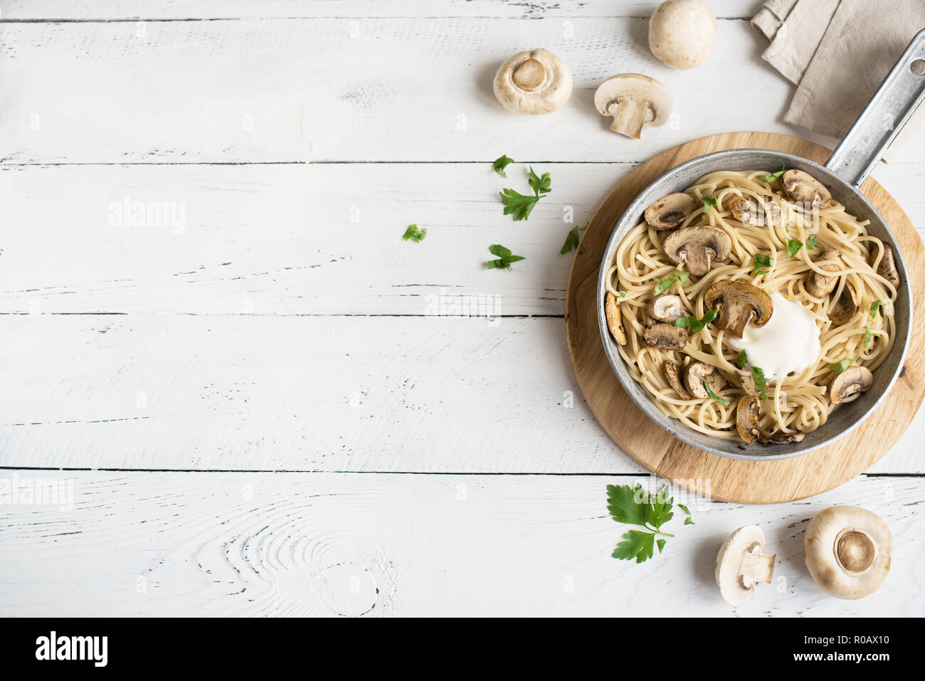 Les pâtes Spaghetti aux champignons et sauce crème sur fond blanc, vue du dessus. Les pâtes italiennes faites maison avec champignon en plat de cuisson. Banque D'Images