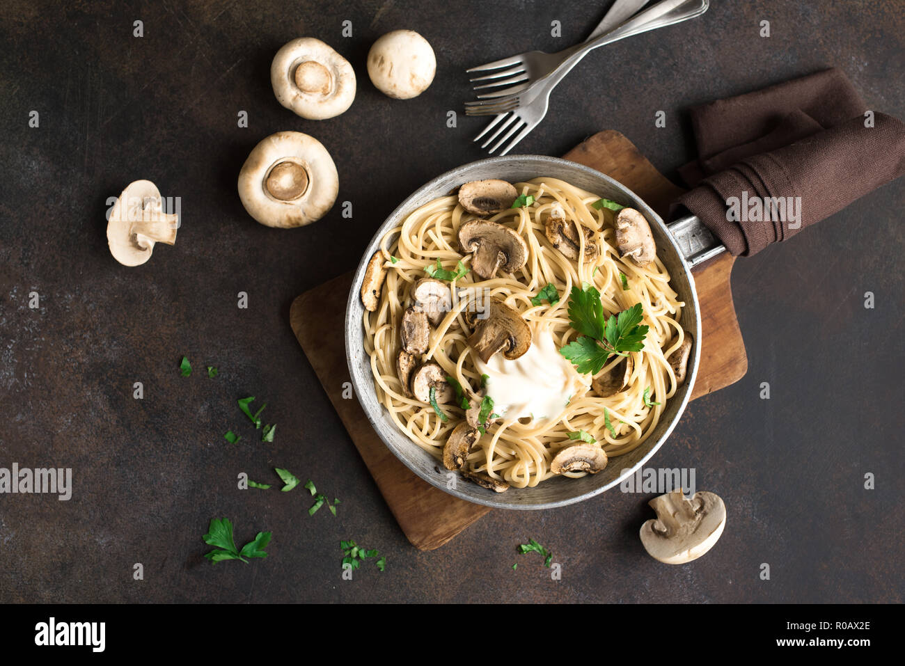 Les pâtes Spaghetti aux champignons et sauce crème sur fond rustique, vue du dessus. Les pâtes italiennes faites maison avec champignon en plat de cuisson. Banque D'Images