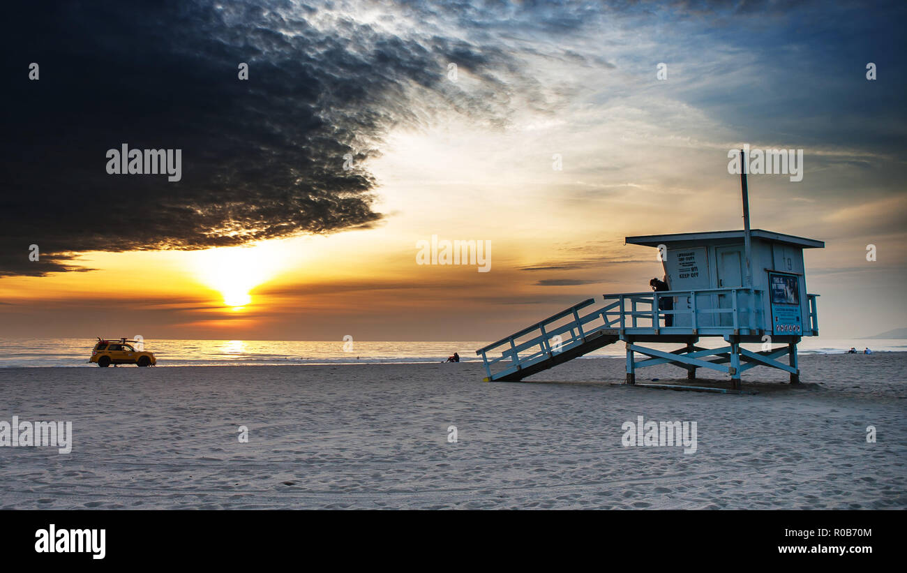 Zuma Beach spectaculaire coucher du soleil, maître-nageur sauveteur Tour en premier plan, car en arrière-plan. Plage vide pendant l'hiver. Banque D'Images