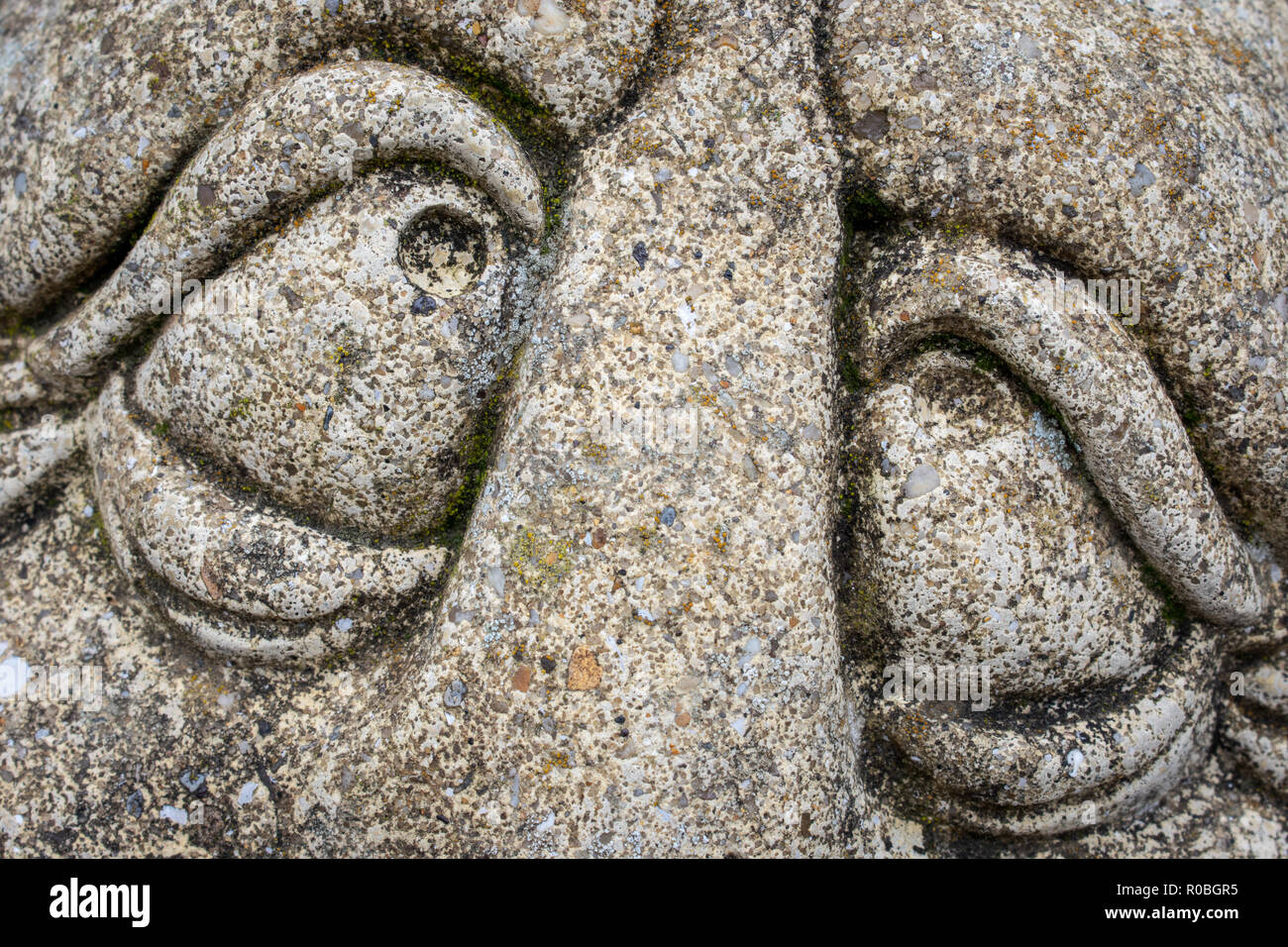 Les yeux fatigués ou gueule de yeux sur un ornement de jardin en pierre Banque D'Images