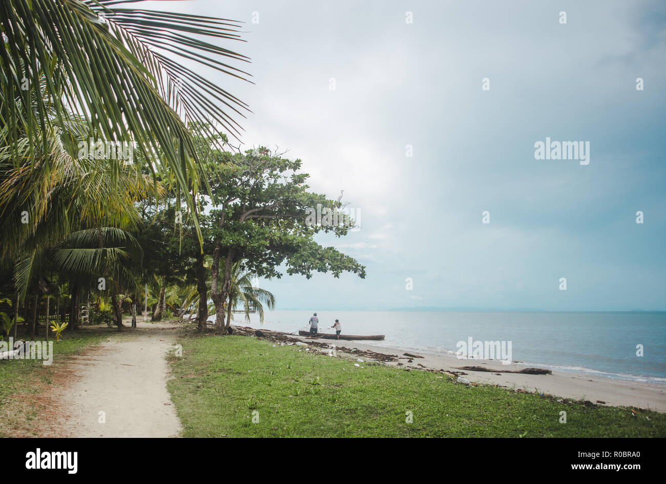 Stand pêcheur guatémaltèque dans la mer des Caraïbes à tirer leurs filets hors de l'eau pour pêcher au large de la côte parsemée de Lívingston, Guatemala Banque D'Images