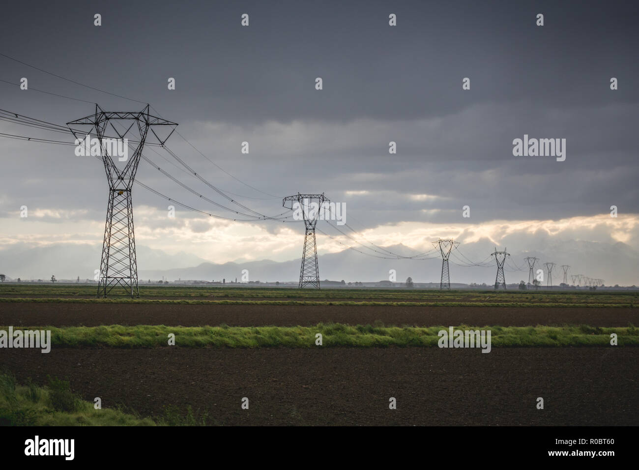Pylônes électriques menant dans un ciel d'orage, Italie Banque D'Images