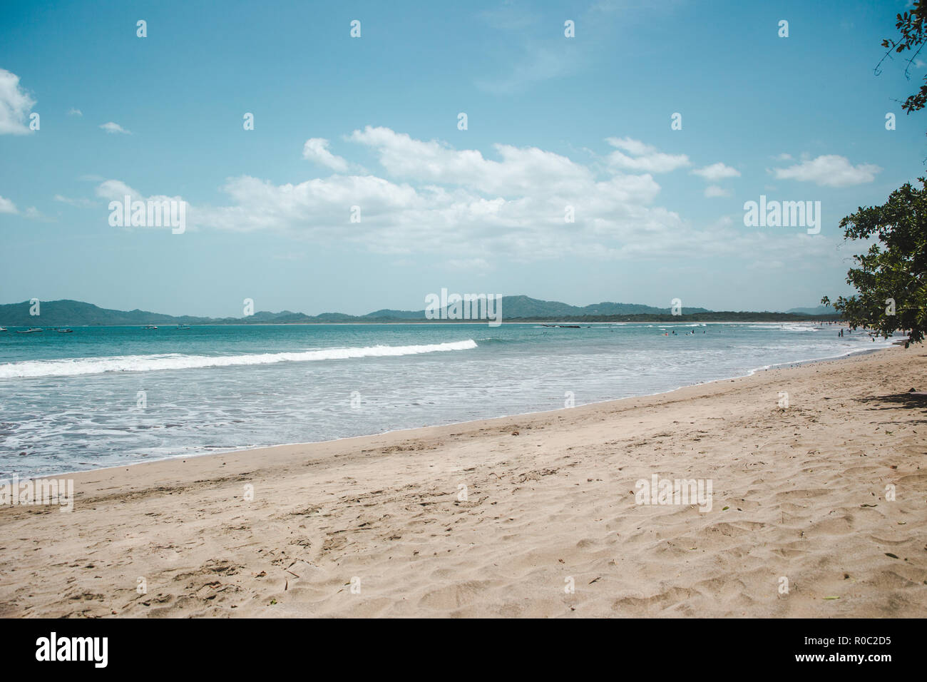 Plage de sable de vide Tamarindo avec les vagues et turquoise montagnes autour de la baie Banque D'Images