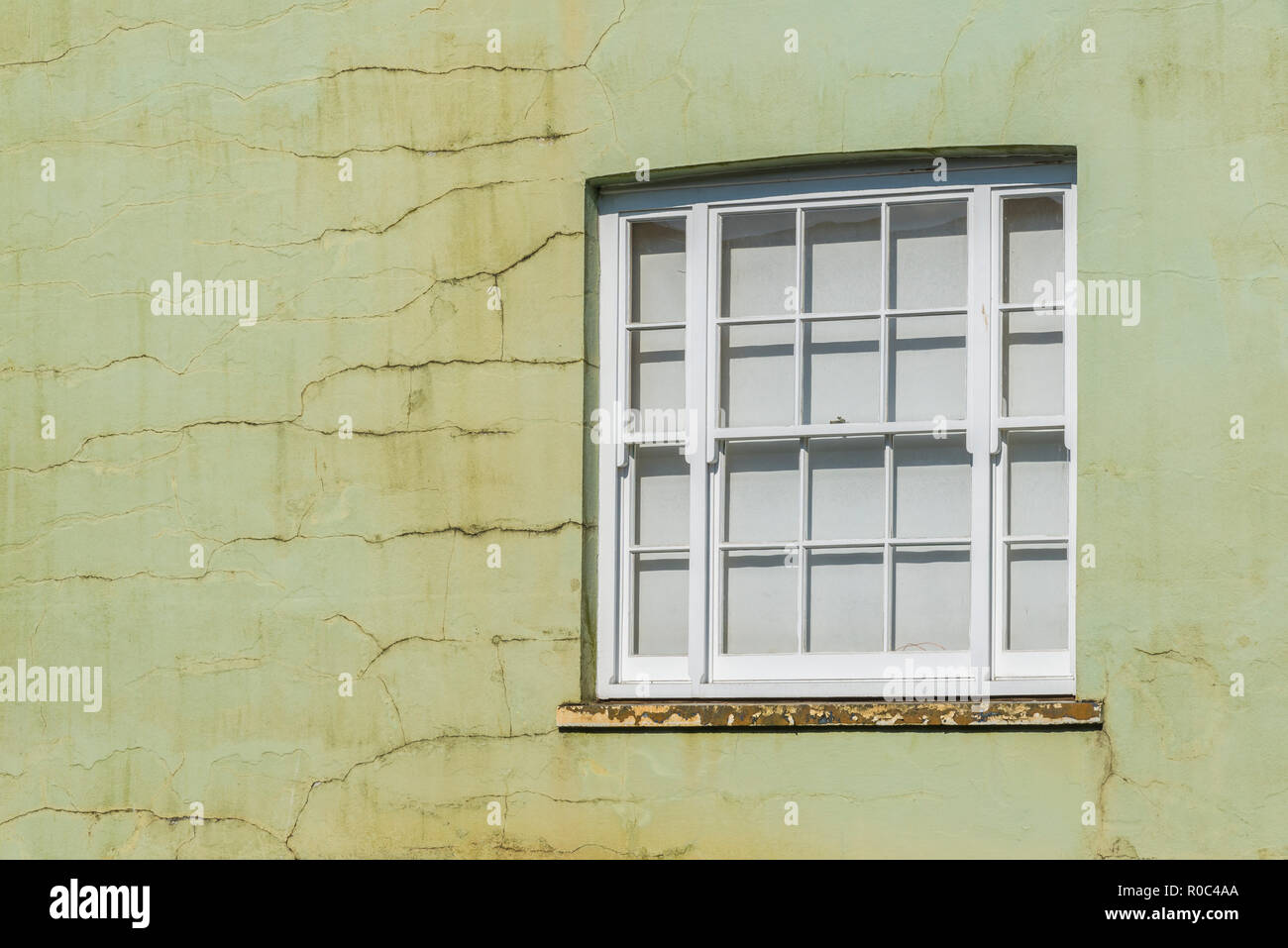 Situé dans la fenêtre du mur du bâtiment fissuré, peint en vert. Les fissures de mur. Banque D'Images