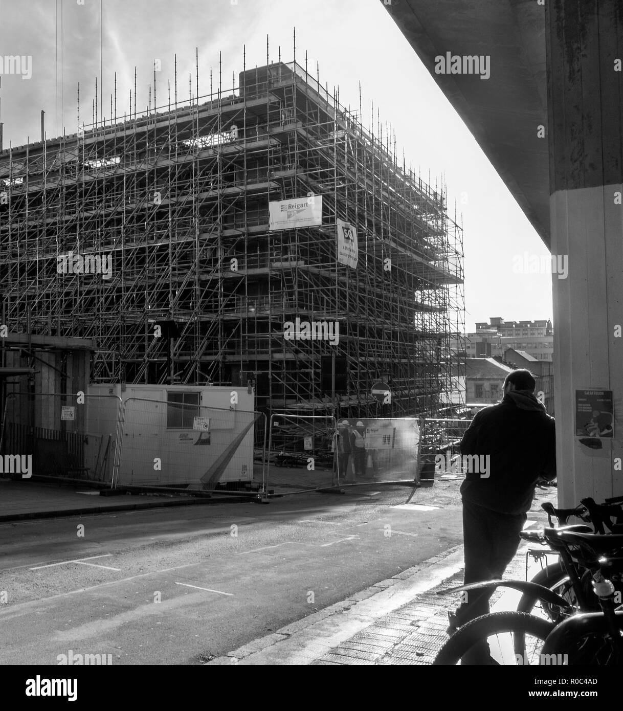 GLASGOW, ÉCOSSE - 2 NOVEMBRE 2018 : une photographie en noir et blanc d'un homme s'appuyant sur un mur pendant que les ouvriers travaillent sur le site de Glasgow School of Art Banque D'Images