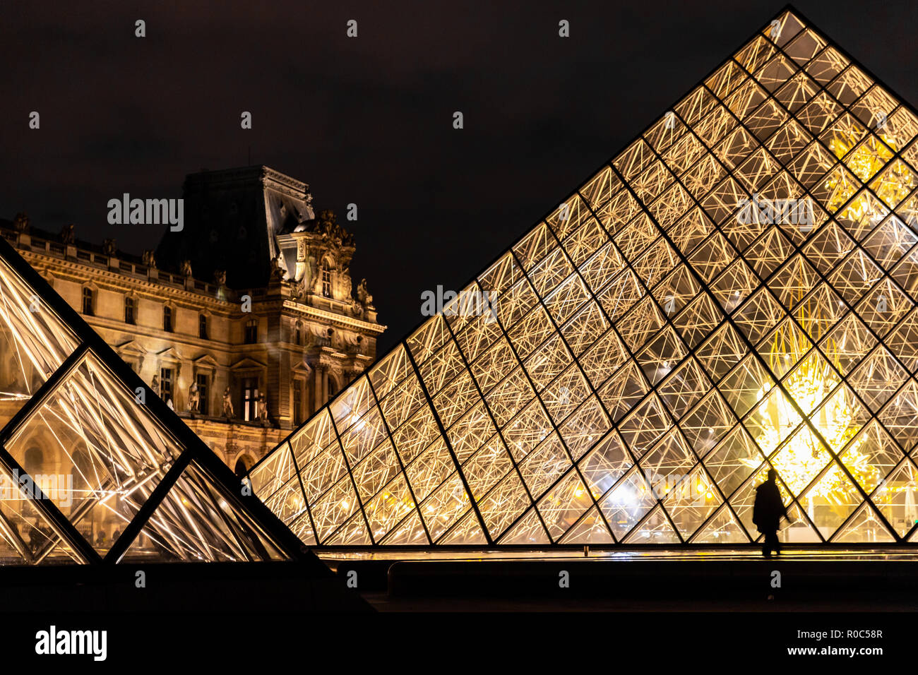 Paris, France - 30 septembre 2018 : la lumière brillante pyramides de verre avec quelques personnes de silhouette du Louvre de nuit. Banque D'Images