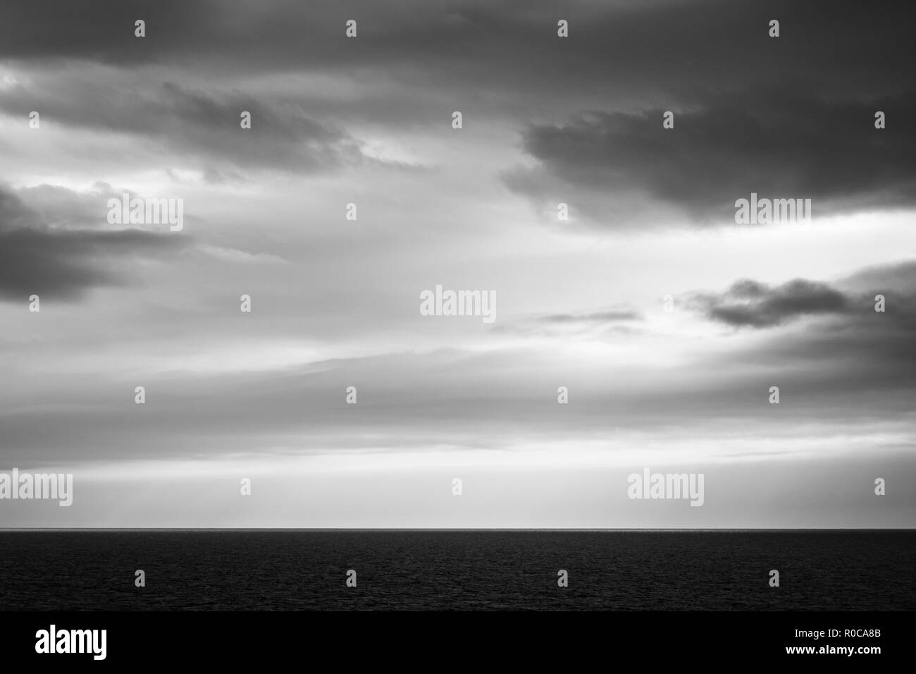 Image en noir et blanc d'imposer ciel nuageux sur une mer plate. Vue de la Madeleine, Québec, Canada. Banque D'Images