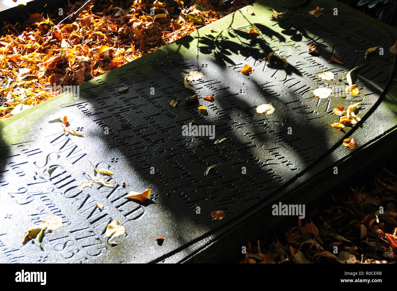 Les feuilles d'automne sur la vieille pierre tombale avec l'écriture Banque D'Images