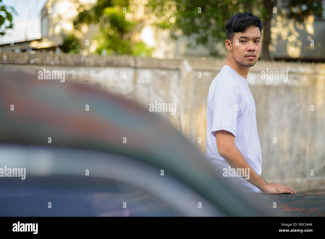 Young Asian man avec vieille voiture rouillée dans les rues à l'extérieur Banque D'Images