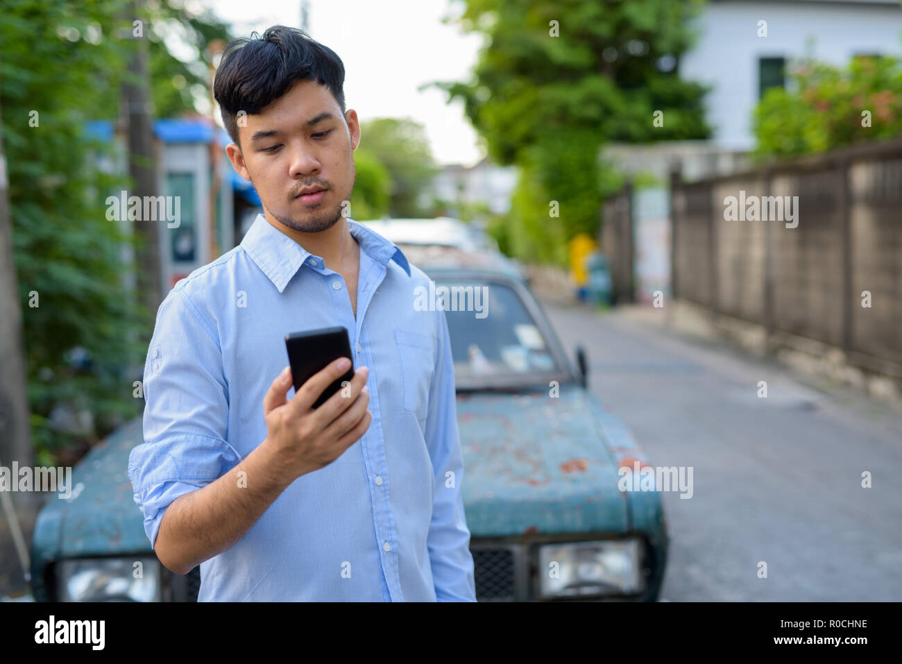 Young Asian Woman contre vieille voiture rouillée Banque D'Images