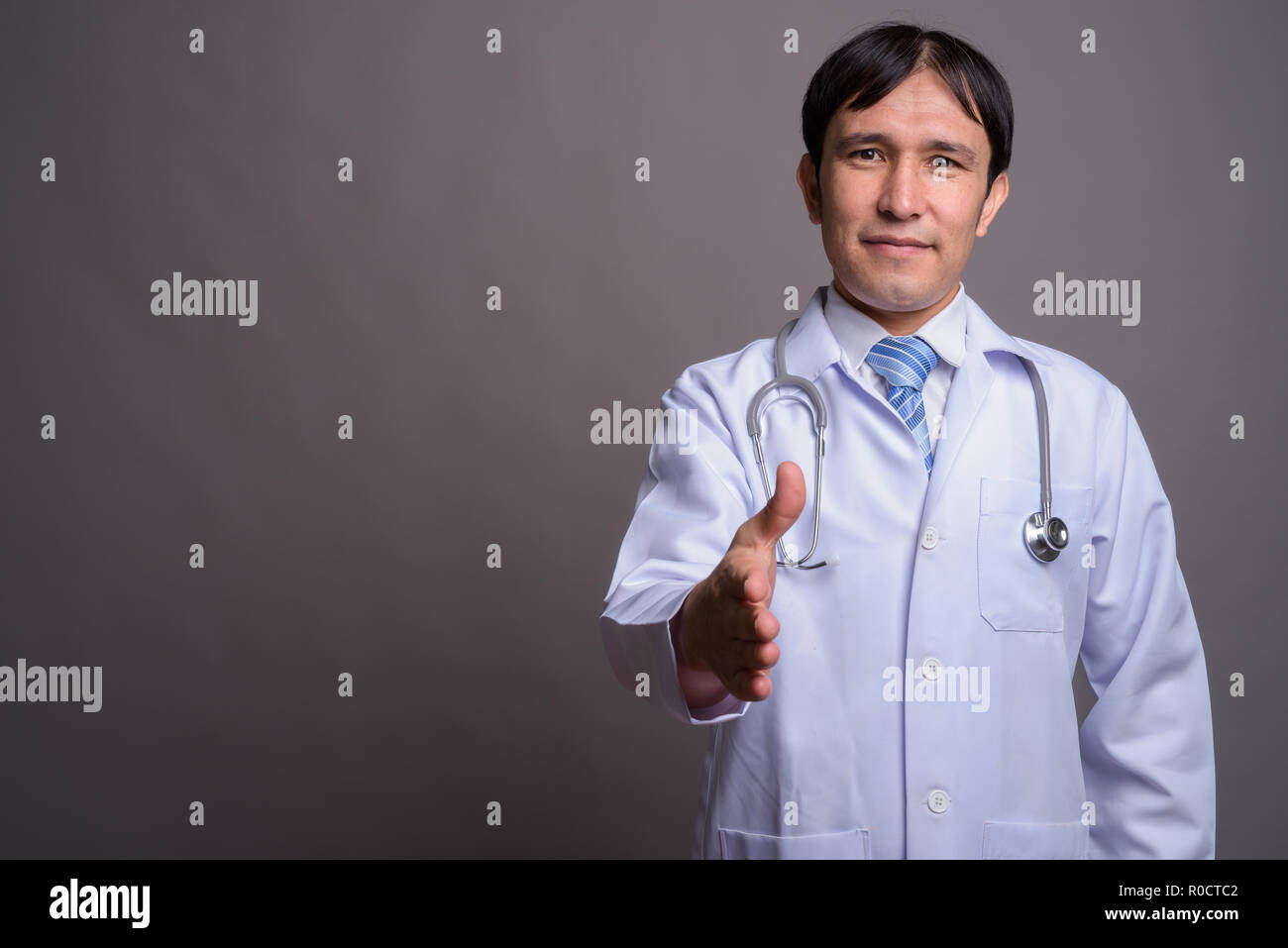 Young Asian man médecin contre l'arrière-plan gris Banque D'Images