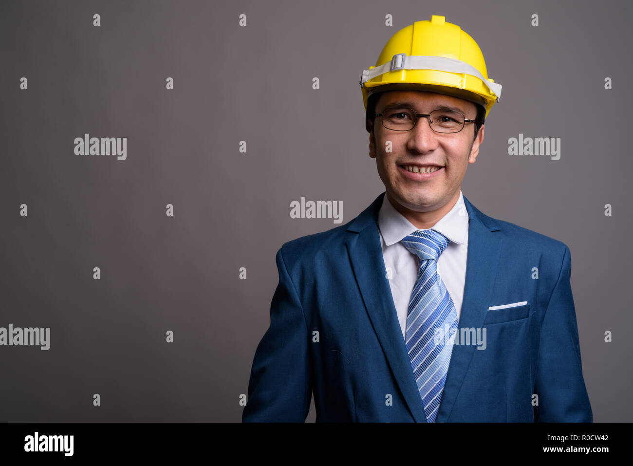 Young businessman wearing hardhat contre l'arrière-plan gris Banque D'Images