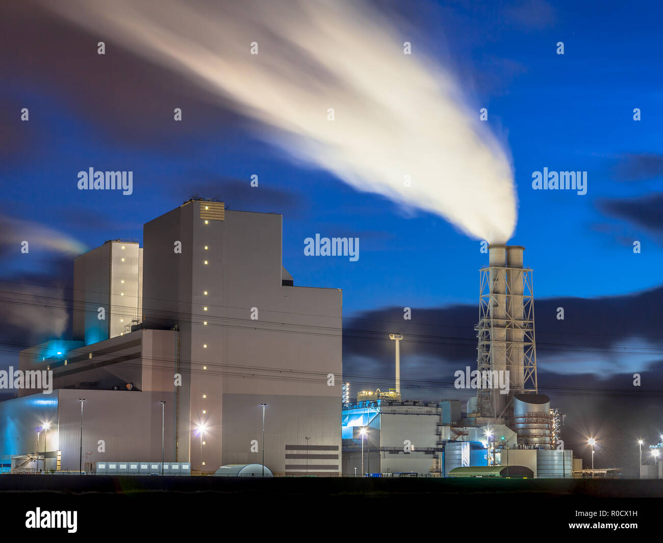 By ultra moderne centrale électrique avec cheminée fumer pendant le coucher du soleil sous un ciel bleu Banque D'Images