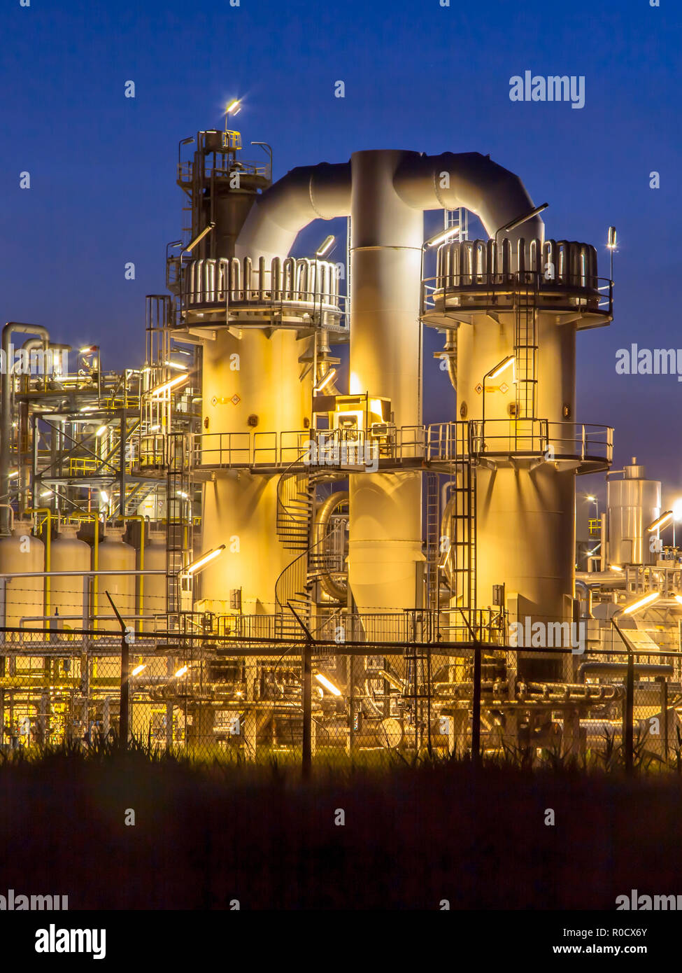 Scène de nuit des détails d'une installation industrielle chimique lourde avec mazework de tuyaux au crépuscule Banque D'Images