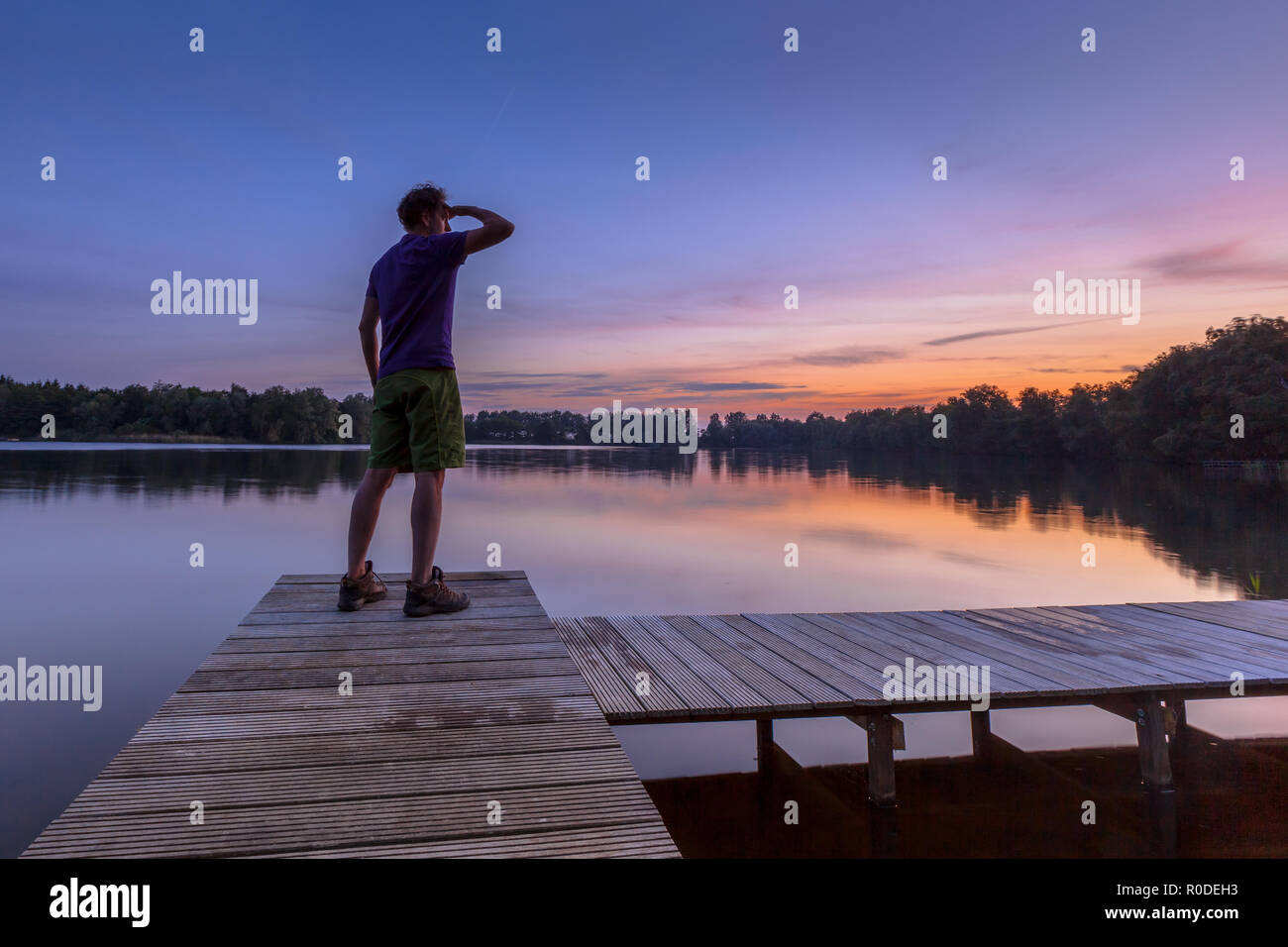L'homme élève son bras tout en appréciant le coucher du soleil comme un concept pour une heureuse réalisation Banque D'Images