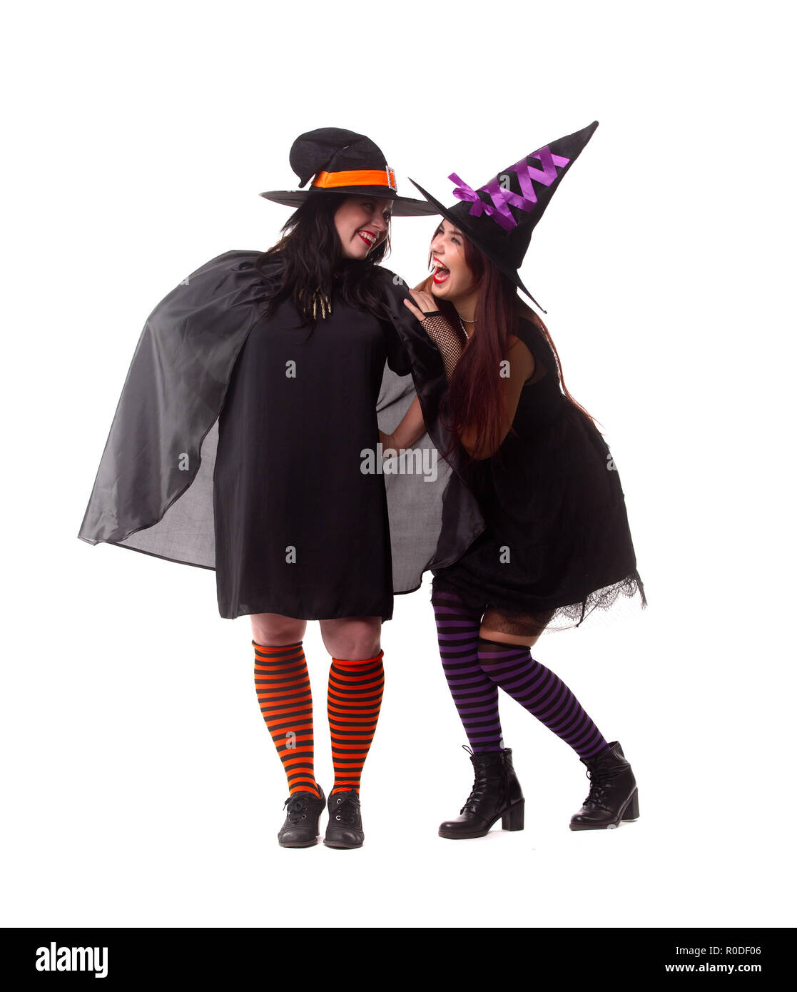 Photo pleine longueur de deux sorcières joyeux porter un chapeau et des chaussettes à rayures Banque D'Images