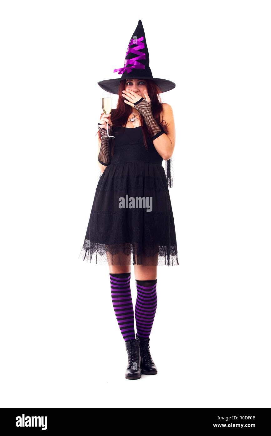 Photo de pleine longueur surpris sorcière avec un verre de vin avec du vin, robe noire, chaussettes rayées Banque D'Images