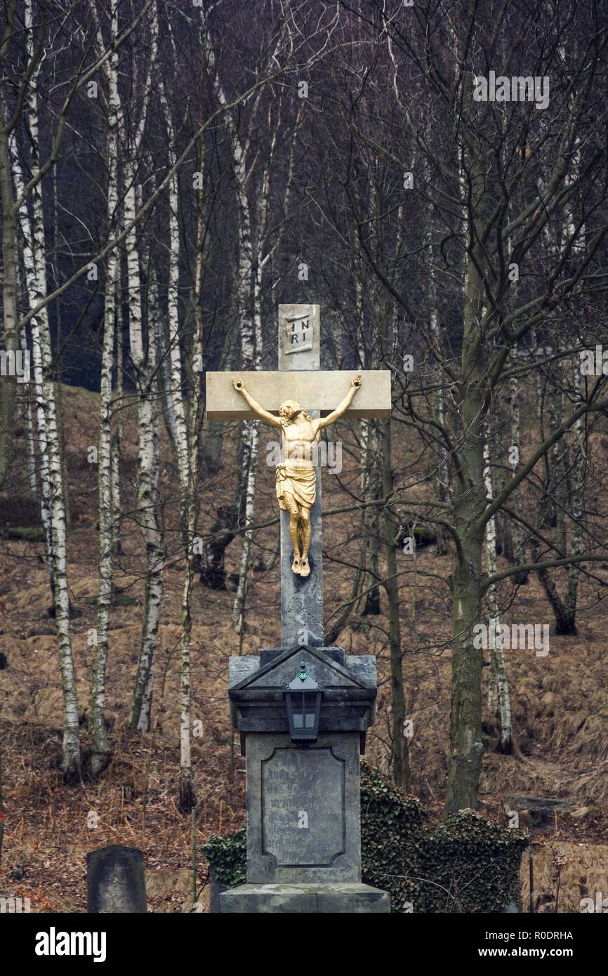 Golden Jésus Christ crucifixion statue, nuageux jour sombre d'hiver, les bouleaux fond mystérieux Banque D'Images