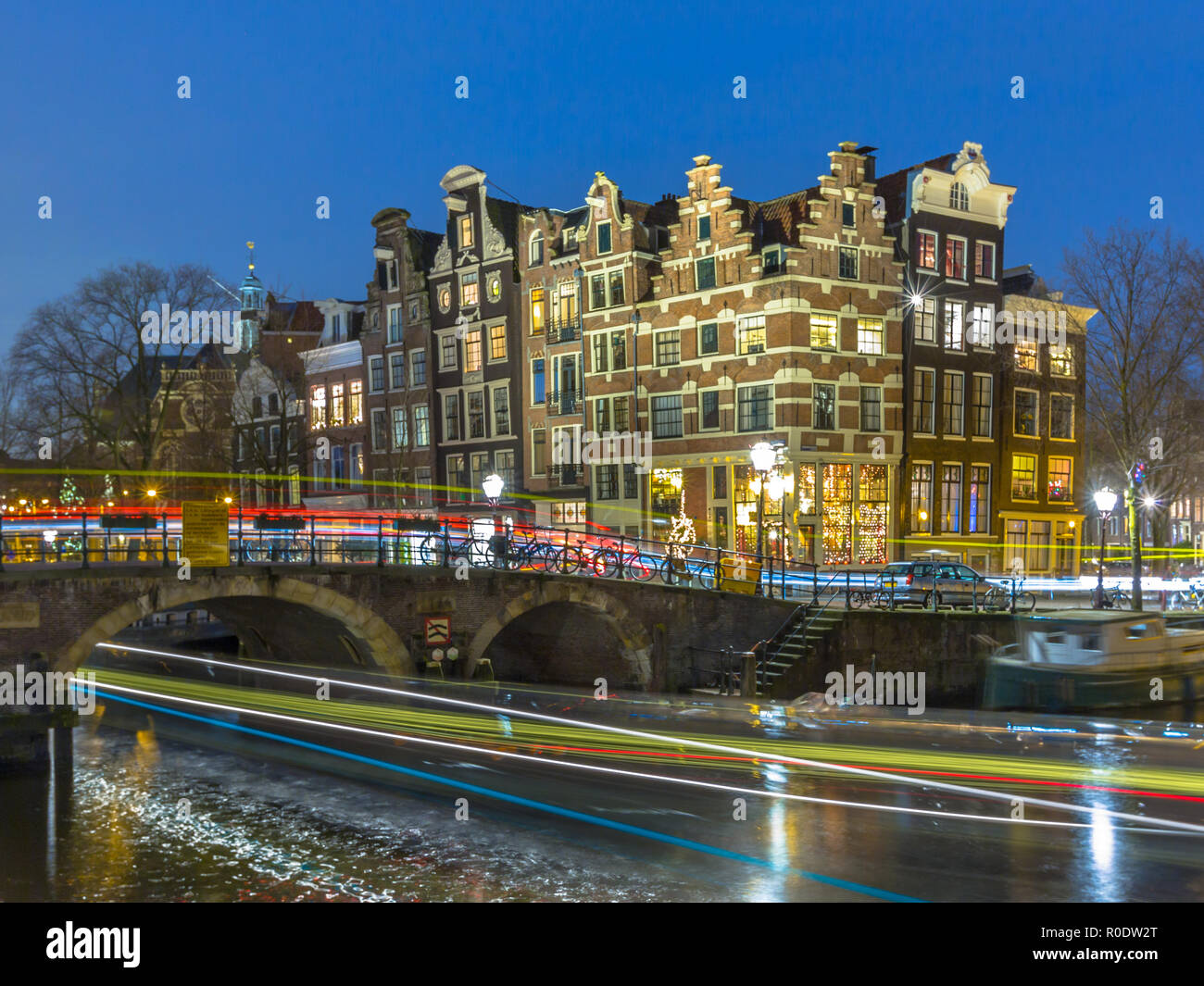 Photo de nuit de maisons traditionnelles colorées avec des bateaux d'excursion et des voitures à l'angle de brouwersgracht et Prinsengracht dans le monde de l'UNESCO Banque D'Images