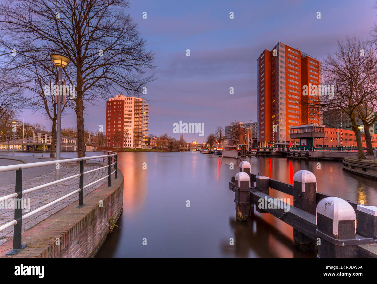Bollard, quai et bâtiments modernes sous un soleil rose ciel au Zuiderhaven Groningen, Pays-Bas Banque D'Images